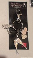 Single blister pack keychain showing 5 bridal themed charms including champagne flutes and wedding dress.
