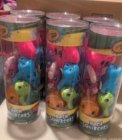 Photo showing three cylindrical clear packages each with 5 colorful Crayola bath squirter sea animal toys inside: pink octopus, blue dolphin, green turtle, orange fish, and beige clam.