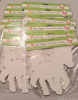 Photo showing twelve unopened packs of white cardstock unicorn shapes, each containing 8 shapes.