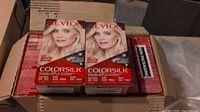 Top view of multiple Revlon Colorsilk hair dye boxes stacked in an open box, showing mainly the front face with product branding and model image.