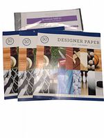 Four packs of Colorbok Designer Paper, each containing 50 sheets of sports-themed 12x12 scrapbook paper plus a small pack labeled Scrapbook Ball Kit, likely containing the 5 protector sheets.