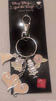 Photo of one bridal themed keychain on black card packaging labeled 'Bling Bling... I Got the Ring!' featuring 5 charms including wedding dress, cake, hearts, bell, flower