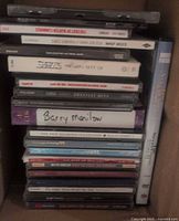 Stack of 21 assorted music CD cases visible with titles and artists from 70s and 80s; mix of singles and box sets.