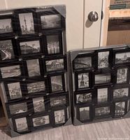 Two large black collage picture frames wrapped in plastic showing multiple cityscape black and white photos.