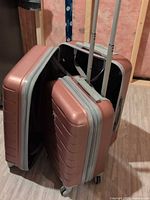 Both suitcases standing side by side with one open showing interior and extended handles