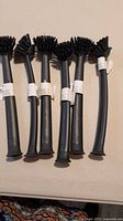 Photo showing six new black IKEA dish scrubbers with curved handles and round brush heads with black bristles.