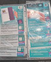 Seven sets of Avery Clear Label index tab dividers and separators in original sealed packaging, shown laid on a flat surface.