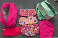Photo showing all eight assorted Clinique bags: two large shiny green, one extra-large pink, and five small patterned bags.