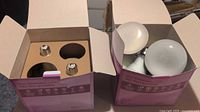 Two open boxes containing Philips LED light bulbs. One box has 2 bulbs and 2 empty spots, the other box has 4 bulbs visible, all with a standard screw base.