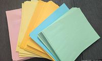 Stacks of colored printer paper sheets in pink, yellow, orange, blue, and green colors shown spread out.