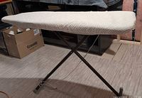 Side view of the full size ironing board showing metal folding legs and beige-white geometric pattern cover.