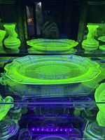 Green uranium glass platter under UV light showing the characteristic glow.