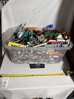 Top view of full plastic container on scale showing bulk LEGO pieces and partial builds, scale reads 13.35 kg