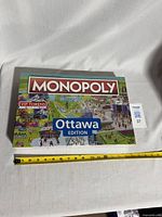 Front view of sealed Monopoly Ottawa Edition board game box with measuring tape for scale.