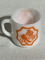 White milk glass coffee mug with orange Busy Bee logo showing full mug and handle.