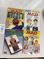 Four vintage Mad Magazine comic books laid out showing colorful covers and variety of pop culture parodies.