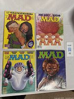 Four Mad Magazine comic books arranged in a grid, showing distinctive covers and logos for each issue.