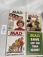 Four vintage Mad Magazine comic books laid out on a white surface, showing front covers with colorful caricature artwork.