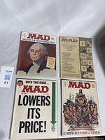 Four Mad Magazine comic books laid flat showing cover art, including Bicentennial themed and Godfather II parody issues.