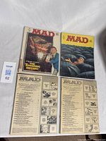 Four vintage Mad Magazine comic books laid out, showing front and back covers.