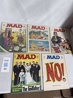 Five vintage Mad Magazine issues displayed side-by-side on table, showing the colorful illustrated covers.