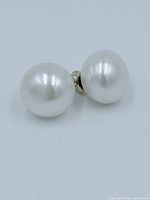 Close-up photo of two white round pearl stud earrings with 10k gold posts.