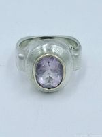 Front view of a chunky sterling silver ring with a polished light purple amethyst set in a 14k gold bezel.