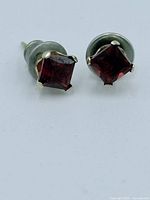 Close-up view of the front of the garnet earrings showing square-cut stones and 4 prong 14k gold setting.