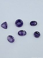 Six loose faceted amethyst gemstones displayed on white background