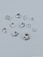 Eleven faceted gemstones arranged on a white background showing transparency and cuts