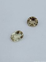 Two faceted citrine gemstones, oval and round shapes, displayed on white background.