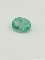 Oval loose emerald gemstone on white background