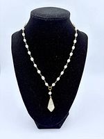 Full necklace displayed on black velvet bust showing pearls and shell pendant