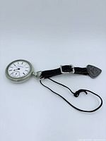 Wide view of pocket watch face, leather strap, and cord