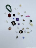 Loose mixed gemstones and pearls arranged on white background.