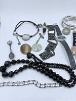 Image showing the lot of mixed watches and jewelry items spaced on a white background, highlighting different items such as watches, necklaces, pendants, bracelets and rings.