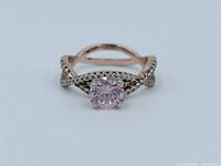 Rose quartz ring front view showing pink faceted center stone and decorative split shank band with accent stones.