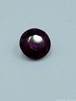 Top view of round cut ruby gemstone showing facets and deep red color.