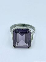 Front view of sterling silver ring with large rectangular purple gemstone in prong setting.
