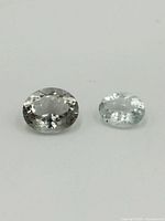 Two oval cut spinel gemstones placed on white background, clearly showing facets and clarity.