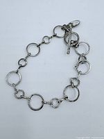 Sterling silver bracelet composed of linked open circular rings with a toggle bar clasp, laid out flat.