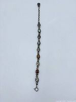 Full view of sterling silver bracelet with six colored gemstones laid flat showing length, clasp, and decorative silver links.