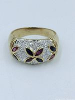 Front view of gold gilt ring showing sapphire and ruby marquise-shaped stones with clear pavé stones on top, detail of design and color.