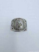 Front view of sterling silver ring with raised Kokopeli figure in oval frame and decorative side engravings.