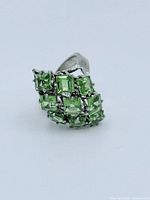 Front and angled view of sterling silver ring showcasing multiple square-cut peridot stones in a raised clustered setting.