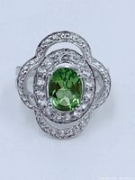 Top view showing oval green peridot gemstone surrounded by two halos of small clear stones set in sterling silver.