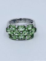 Front view of sterling silver ring with eight oval peridot stones clustered in two rows of four.