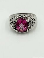 Front view of sterling silver ring with oval pink sapphire center stone and decorative filigree sides.