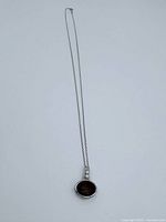 Full view of the sterling silver necklace with brown oval pendant on chain.