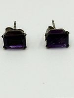 Front view of two amethyst stud earrings set in sterling silver with four-prong settings on a white background.